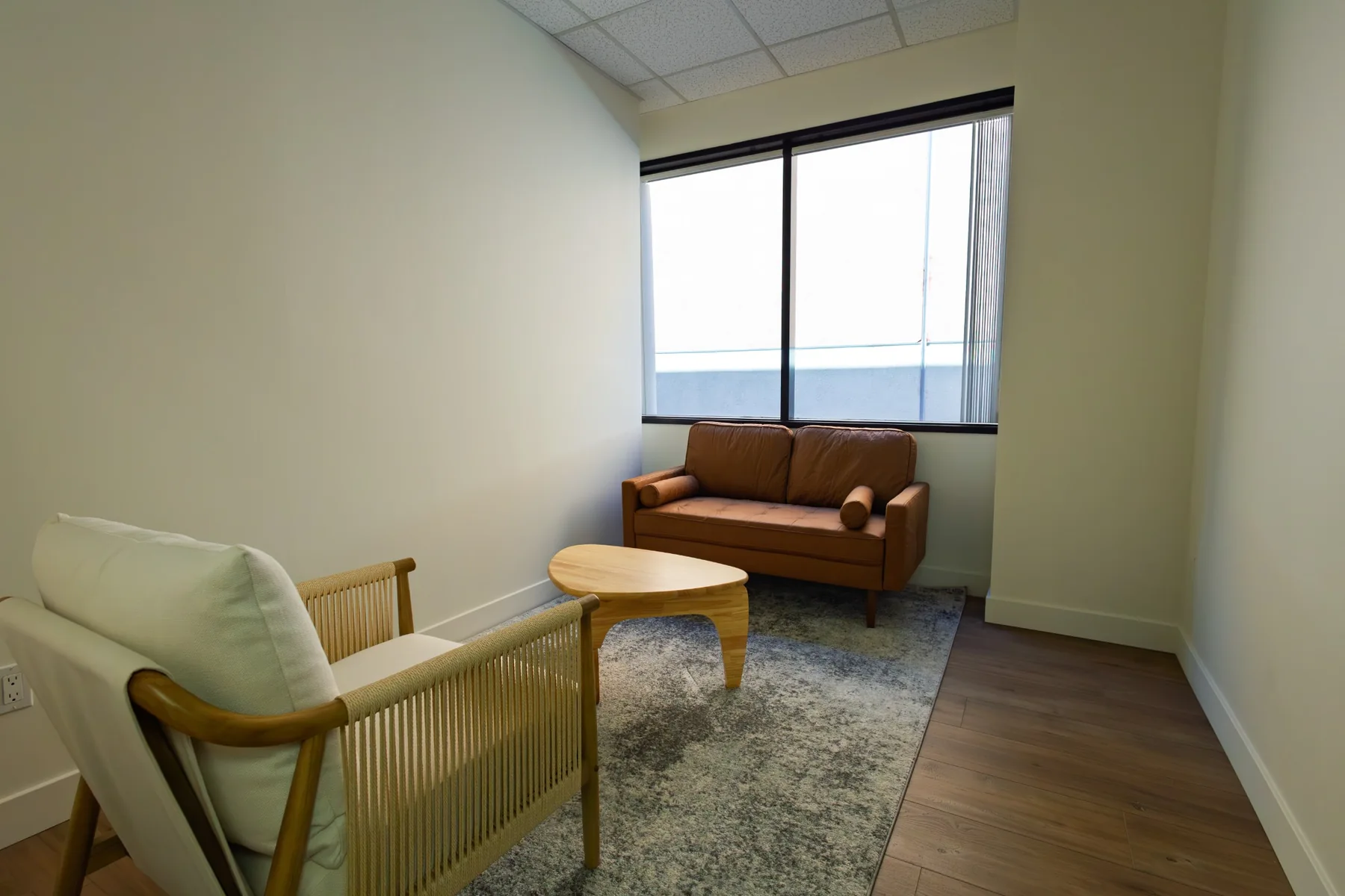 Private office with a sofa, armchair, and window